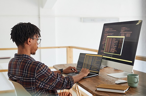 Network administrator in front of a laptop and a monitor