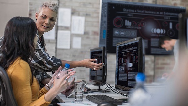 女性技术人员在仪表盘屏幕前合作