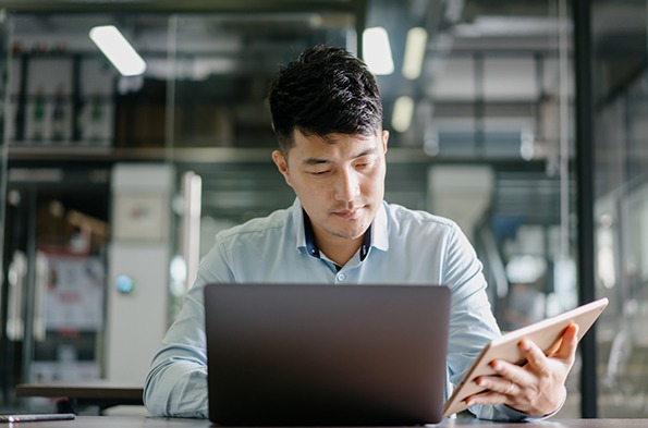 Young man working on multiple devices at his office desk