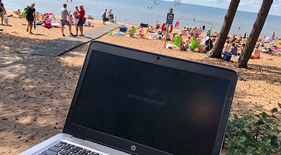 在海滩上显示登录屏幕的笔记本电脑