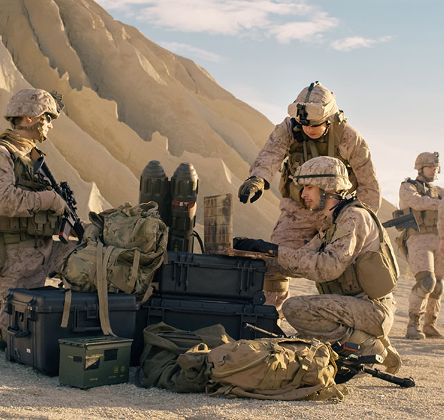 U.S. troops working on a mobile device in a desert setting