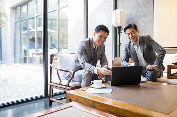 两个男人在公司会议室的笔记本电脑前开会