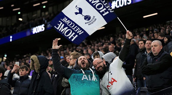 Fans waving a club flag during the football game next to a fan holding up a mobile phone