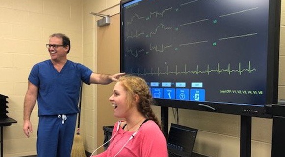 A medical professional in scrubs presenting medical monitor readouts to the kids